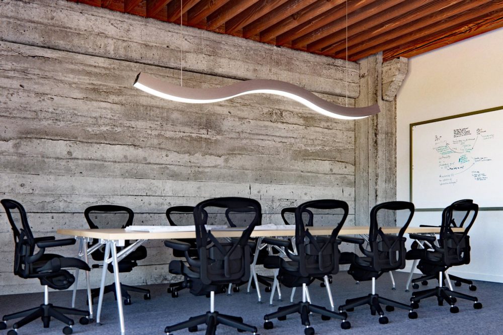 PMC ArcX wavy linear lighting suspended over a meeting table